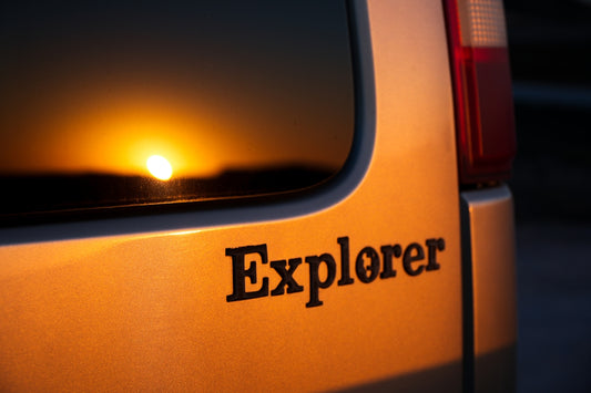 A close up of the back of a vehicle with the sun setting in the background